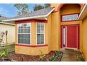 Front entrance with a red door and a bay window at 7872 Niagara Falls Ct, Orlando, FL 32825