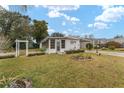 Landscaped yard and manufactured home with white siding at 807 Maple Ln, The Villages, FL 32159