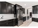 Modern kitchen with dark cabinets, stainless steel appliances, and a large island at 848 Carmillion Ct, Groveland, FL 34736