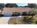 Single-story house with a brown roof, attached garage, and a palm tree in the front yard at 13709 Se 89Th Ave, Summerfield, FL 34491