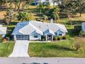 Single-story house with gray roof, attached garage, and green lawn at 27039 Racquet Cir, Leesburg, FL 34748