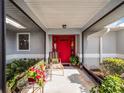 Covered entryway with red door, seating area, and potted plants at 27039 Racquet Cir, Leesburg, FL 34748