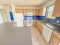 Traditional kitchen featuring light wood cabinets, white appliances, and a tiled floor at 2707 Privada Dr, The Villages, FL 32162