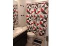 Bathroom featuring a single sink vanity and toilet with a black, gray, and red shower curtain at 37030 Lake Overlook Dr, Grand Island, FL 32735