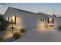 White house with two-car garage and landscaped front yard at night at 446 Flossmoor Ct, The Villages, FL 32162
