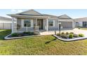 Gray house with a white porch and landscaping at 6764 Mary Loop, The Villages, FL 34762