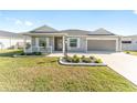 Gray house with a white porch and landscaping at 6764 Mary Loop, The Villages, FL 34762