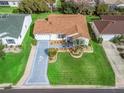 Aerial view of a single-Gathering home with lush green lawn, well-manicured landscaping and a painted driveway with palm tree accents at 17412 Se 76Th Flintlock Ter, The Villages, FL 32162
