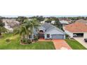 House with gray exterior, brick paver driveway, and palm trees at 3201 Darien Way, The Villages, FL 32162