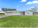 Gray house with teal accents, two-car garage, and spacious lawn at 9897 Se 178Th Pl, Summerfield, FL 34491