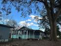 Quaint blue home with sunroom windows, a covered porch, and a spacious yard with mature trees at 13369 Cr 719, Webster, FL 33597