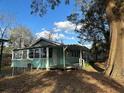 Charming blue house with a covered porch and sunroom windows, nestled among mature trees at 13369 Cr 719, Webster, FL 33597