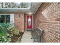 Elegant front entrance with a red door, decorative window, bench, and brick facade at 3450 Laurel Dr, Mount Dora, FL 32757