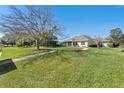 Expansive green backyard with mature trees and walkway leading to the rear screened-in porch at 6026 Landings Blvd, Lady Lake, FL 32159