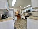 Well-lit kitchen featuring modern appliances, granite counters, tile backsplash and unique stone-look flooring at 106 Gardenia Way, Leesburg, FL 34748