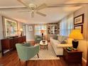 Bright living room with comfortable seating, hardwood floors, complemented by neutral walls, a ceiling fan, and natural light at 106 Gardenia Way, Leesburg, FL 34748