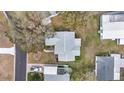 An aerial view of a single story home with a neutral roof and landscaping, nestled among mature trees at 1613 Cherry Hill Rd, The Villages, FL 32159