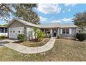Charming single-story home with gray siding, well-manicured lawn, and a welcoming front porch at 1613 Cherry Hill Rd, The Villages, FL 32159