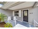 A cozy front porch featuring stylish seating, a decorative front door with house number, and fresh landscaping at 1613 Cherry Hill Rd, The Villages, FL 32159