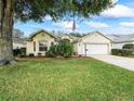 Charming one-story home boasting a lush green lawn, mature trees, and a two-car garage at 16814 Se 80Th Bellavista Cir, The Villages, FL 32162