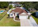 Well-manicured lawn and garden lead up to this cream-colored single Gathering home with a red door and two-car garage at 177 Boardman Dr, Umatilla, FL 32784