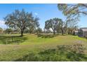 Expansive grassy backyard featuring mature trees and a picturesque view of the golf course at 3518 Westerham Dr, Clermont, FL 34711