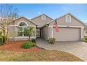 Beautiful neutral home with an attached two-car garage, a brick driveway, and decorative shrubs at 3518 Westerham Dr, Clermont, FL 34711