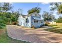 Side view of a charming home featuring a spacious brick driveway, lush landscaping, and a fenced yard at 805 Hackett Ct, Mount Dora, FL 32757