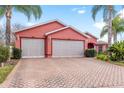 Brick driveway and three-car garage with screened doors at 1130 Meadowbend Dr, Leesburg, FL 34748