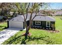 Well-kept single-story home with mature trees, a two-car garage, and a tidy front yard at 1511 Moss Ave, Leesburg, FL 34748