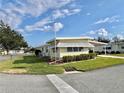 Side view of a yellow single story home showcasing manicured lawn at 180 Hibiscus Way, Leesburg, FL 34748