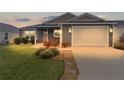 Charming single-story home featuring a well-manicured lawn and attached garage at dusk at 284 Pelchat Pl, The Villages, FL 32163