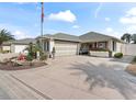 One-story home with gray roof, red flowers, and a paved driveway at 2987 Schoenacher St, The Villages, FL 32163