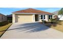 House exterior featuring a light-yellow painted exterior, attached garage, and driveway at 3180 Dressendorfer Dr, The Villages, FL 32163