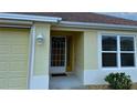 Front entry with a yellow-painted exterior, a glass front door, and a lantern light at 3180 Dressendorfer Dr, The Villages, FL 32163