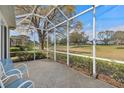 Screened-in porch overlooking green space, featuring a tiled floor and blue chairs for relaxing outdoors at 3637 Hawkshead Dr, Clermont, FL 34711