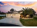 Beautifully landscaped home with a three-car garage and a paver driveway at sunset at 4515 Biggs Pl, The Villages, FL 32163