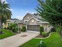 Two-story house with a screened porch, two-car garage, and landscaped yard at 4985 Rainbow Trout Rd, Tavares, FL 32778