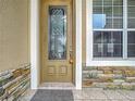 Front door with a decorative glass insert and stone accents at 4985 Rainbow Trout Rd, Tavares, FL 32778