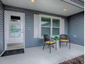 Inviting front porch with seating, a decorative door, and neutral siding adding charm to the home at 802 Nancy Dr, The Villages, FL 32163