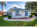 Charming single story home with blue trim, manicured landscaping, and a sidewalk-lined walkway at 85 Golfview Cir, Umatilla, FL 32784