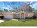 Front view of a single-story house with a garage and neat landscaping at 870 Vindale Rd, Tavares, FL 32778