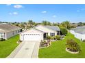 Well-maintained home exterior showcasing a green lawn, tidy landscaping, and two car garage at 893 Fenwick Loop, The Villages, FL 32163