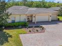 Beautiful home with a brick driveway, three car garage, manicured lawn, and tastefully planted greenery at 917 Shorehaven Dr, Poinciana, FL 34759