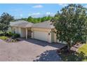 Charming home with a brick driveway, lush green lawn, black iron gate, and a three-car garage at 917 Shorehaven Dr, Poinciana, FL 34759