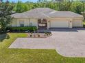 Beautiful home featuring a brick driveway, three car garage, manicured lawn, and tasteful landscaping at 917 Shorehaven Dr, Poinciana, FL 34759