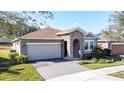 Single-story home featuring a stone entryway, two-car garage, well-maintained lawn, and beautiful landscaping at 96 Silver Maple Rd, Groveland, FL 34736