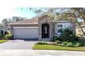 Single-story home featuring a stone entryway, two-car garage, well-maintained lawn, and beautiful landscaping at 96 Silver Maple Rd, Groveland, FL 34736