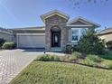 Charming exterior view of the house featuring a stone archway and meticulously manicured landscaping at 96 Silver Maple Rd, Groveland, FL 34736