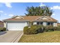 Front view of a single-story house with a two-car garage and landscaped yard at 3001 Saint Thomas Ln, The Villages, FL 32162